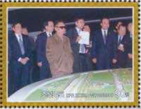 Colnect-2954-885-Kim-Jong-Il-in-front-of-a-model-of-a-landscape.jpg