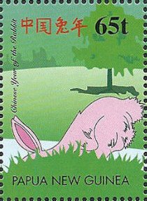 Colnect-2220-923-Pink-rabbit-hiding-behind-grass-knoll.jpg